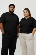 Two models wearing black crewneck t-shirts and casual pants, standing against a light gray studio background.