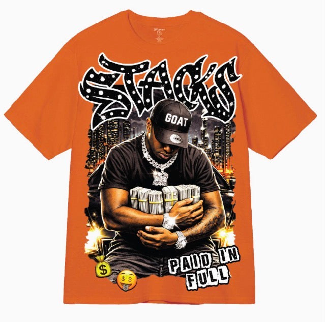An orange short-sleeve graphic t-shirt featuring a large front print of a man in a black cap reading 'GOAT' and holding stacks of cash, with stylized text reading 'STACKS' and 'PAID IN FULL'.